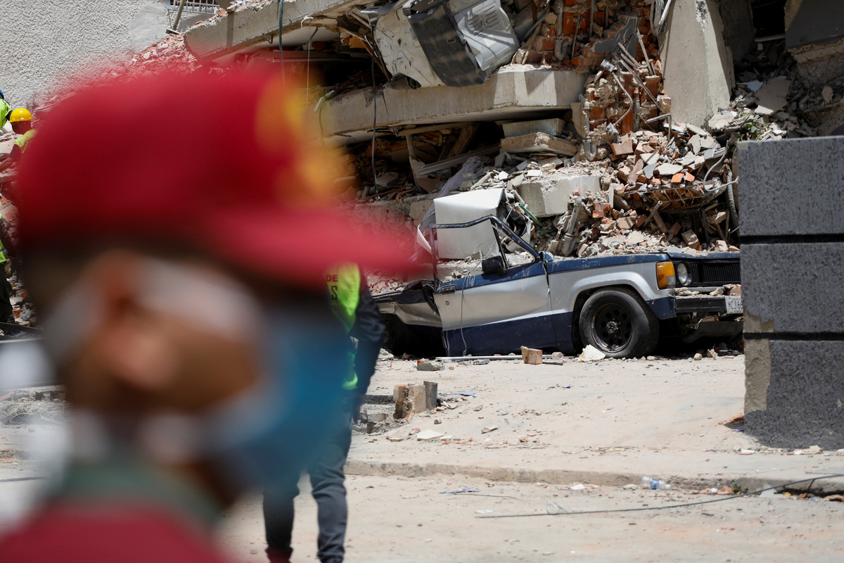 A damaged car is seen as emergency services work at the site of a collapsed building following earthquakes that hit the country, in Caracas, Venezuela, June 26, 2026. REUTERS/Fausto Torrealba