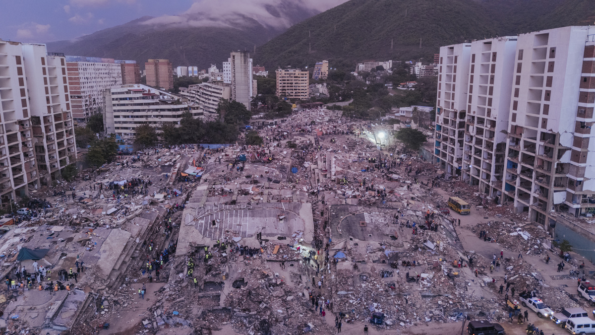 Rescuers work at dusk amid a group of collapsed residential buildings in La Guaira, Venezuela, June 30, 2026. After devastating twin earthquakes flattened entire residential neighborhoods last week, experts fear the official death toll of 1,719 could be a serious undercount. (Adriana Loureiro Fernandez/The New York Times)