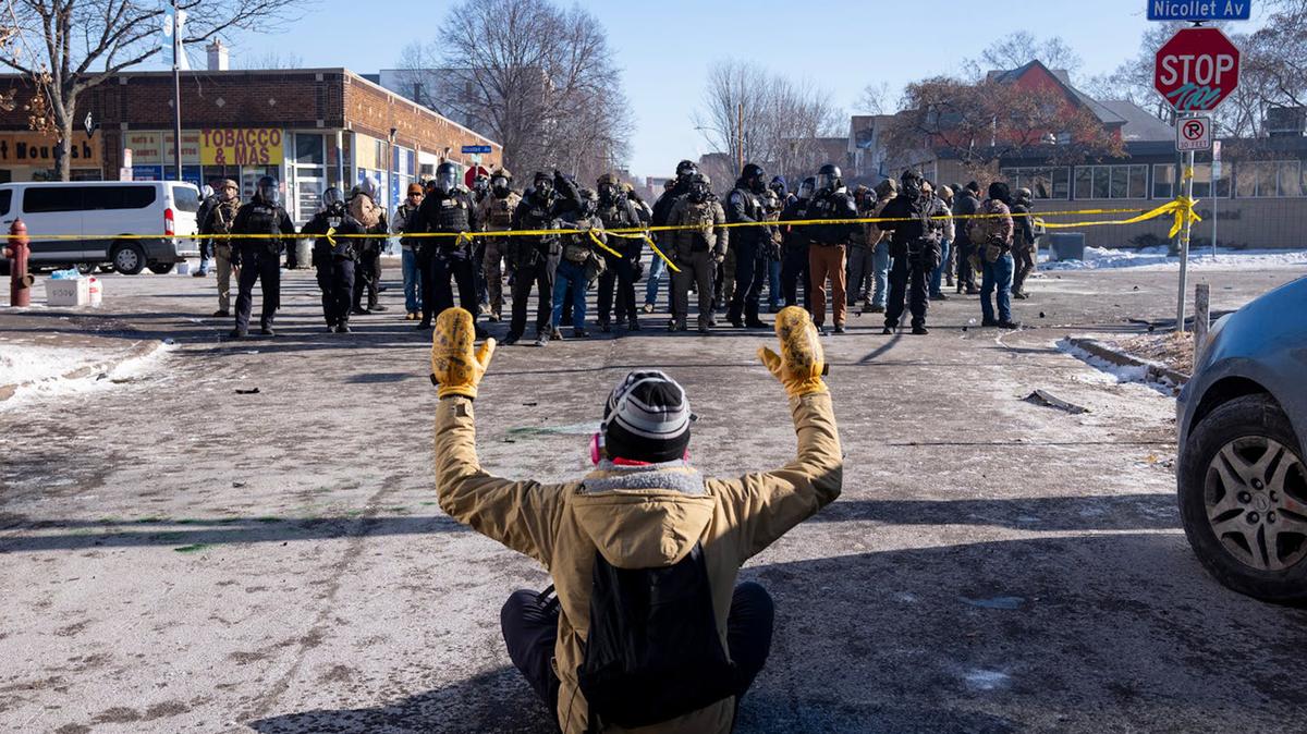 A protester sits in the street in front of a group of federal agents and Minneapolis police officers at West 27th Street and Nicollet Avenue after federal agents fatally shot Alex Pretti on Jan. 24, 2026, in Minneapolis. (Alex Kormann/The Minnesota Star Tribune/TNS)