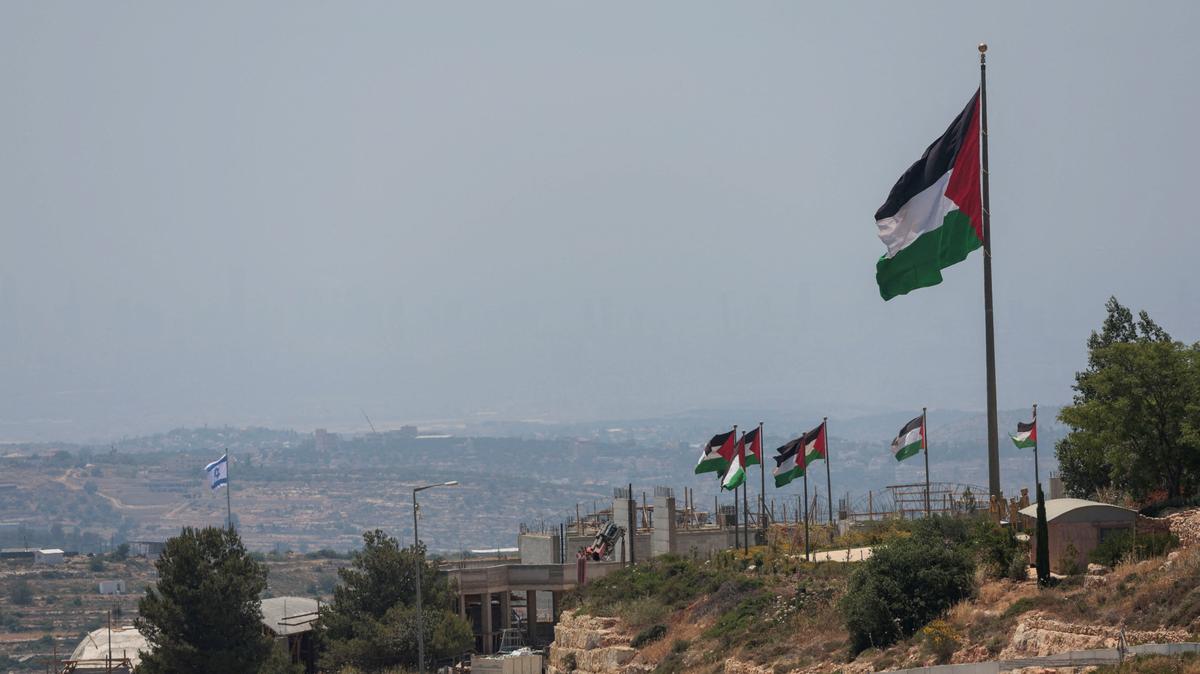 An Israeli flag flutters at a new Israeli settlement, behind Palestinians flags near Ramallah, in the Israeli-occupied West Bank, Jun 1, 2026. REUTERS/Mohammed Torokman