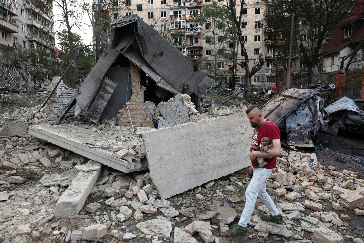 A man carrying a dog walks amidst rubble following overnight Russian missile and drone strikes, amid Russia’s attack on Ukraine, in Kyiv, Ukraine, July 2, 2026. REUTERS/Alina Smutko