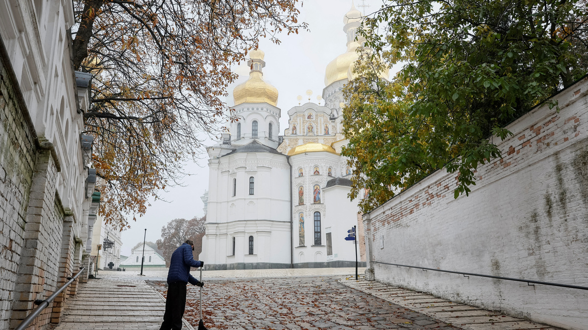 A man sweeps leaves side of a church at a compound of the Kyiv Pechersk Lavra monastery, amid Russia's attack on Ukraine, in Kyiv, Ukraine, October 20, 2023. REUTERS/Alina Smutko