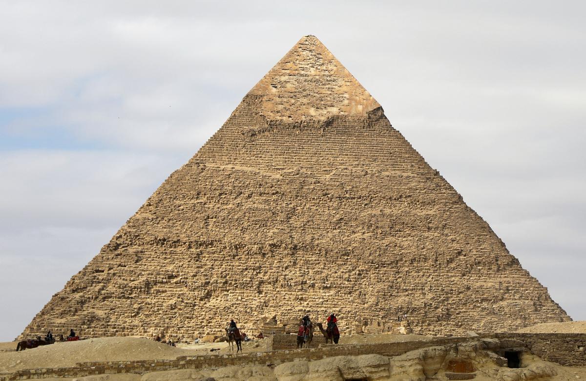 FILE PHOTO: Camel guides wait for customers in front of the Pyramid of Khufu, the largest of the Great Pyramids of Giza, on the outskirts of Cairo, Egypt January 18, 2020. REUTERS/Marius Bosch/File Photo
