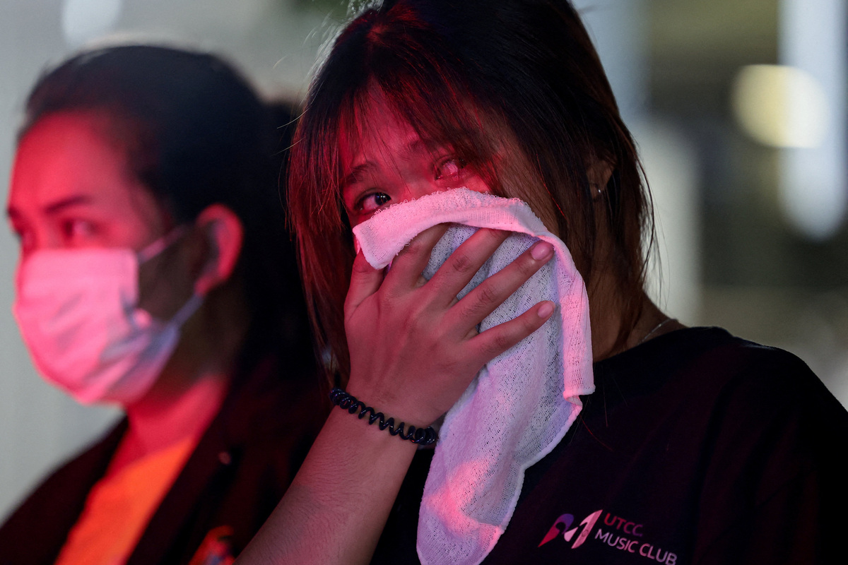 A woman, whose older sister died in a fire at a pub in Bangkok, reacts near the scene, Thailand, July 13, 2026. REUTERS/Chalinee Thirasupa