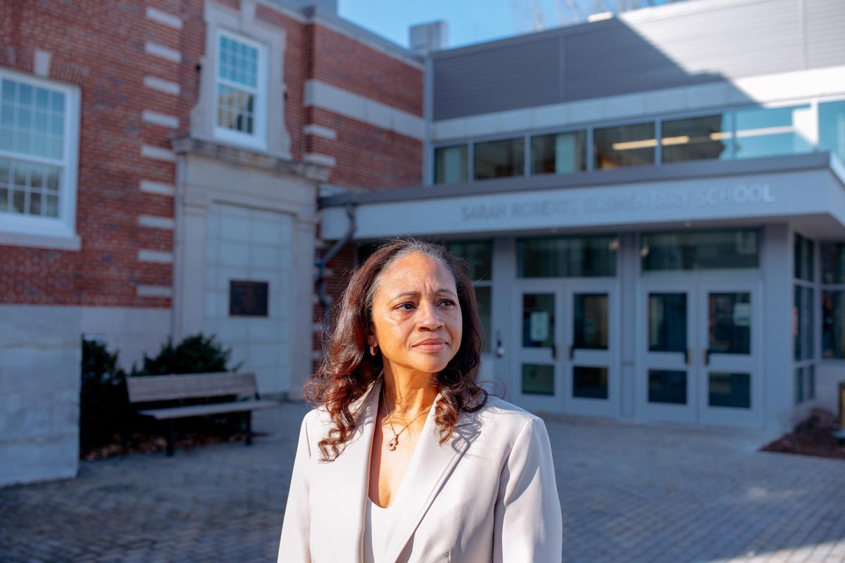  Claire Galloway-Jones, who lost her job as Brookline's equity office director after a school committee vote to shutter the office last spring, stands outside Sarah Roberts Elementary School in Roslindale, Massachusetts. The school is named after her ancestor, who was part of the first family in the country to challenge school segregation. Credit: Marianna McMurdock for The Hechinger Report