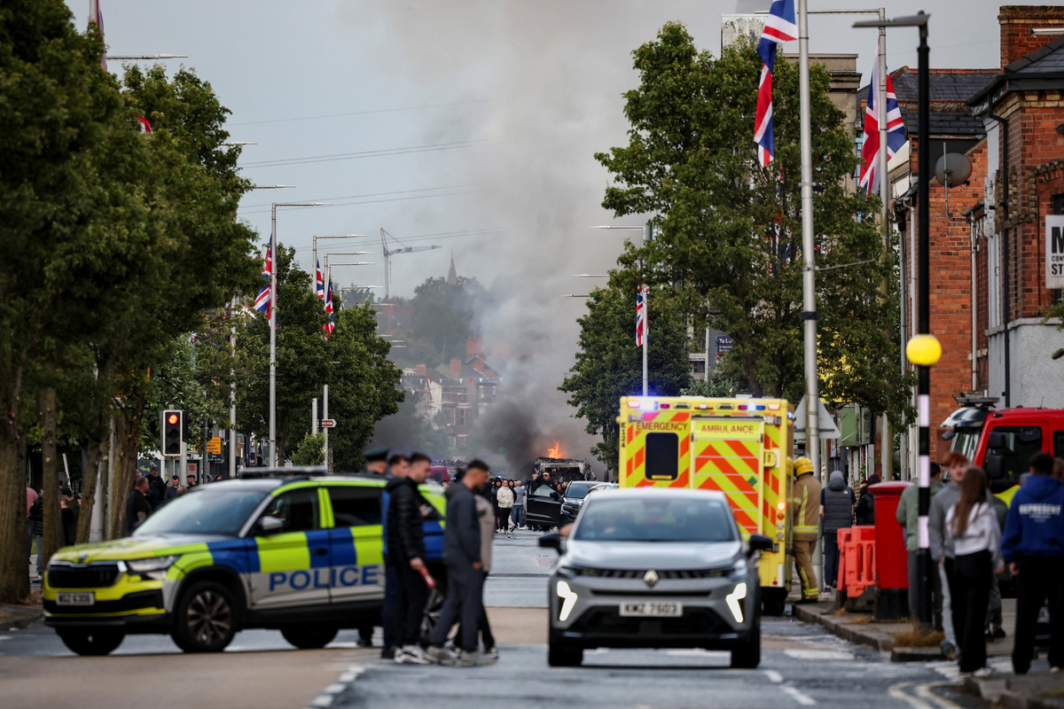 Law enforcement operates as smoke billows from a burning vehicle during a protest after a knife attack on June 8 left a man seriously injured and prompted police to declare a critical incident, on Newtownards Road in Belfast, Northern Ireland, June 9, 2026. REUTERS/Isabel Infantes