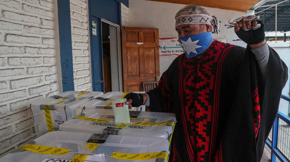 Un indígena mapuche conocido como Clay deposita su voto en una mesa de votación durante el segundo día de la elección de la Convención Constitucional para seleccionar a los miembros de la asamblea que redactarán una nueva Carta Magna, en Santiago de Chile, el domingo 16 de mayo de 2021. (Foto AP/Esteban Félix)