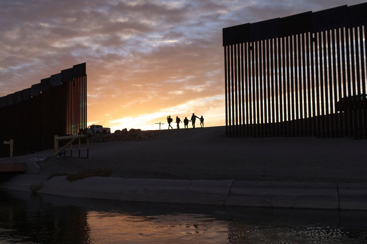 Familias migrantes de Brasil atraviesan una brecha en el muro fronterizo para llegar a Estados Unidos después de cruzar desde México en Yuma, Arizona, para buscar asilo, el 10 de junio de 2021.
