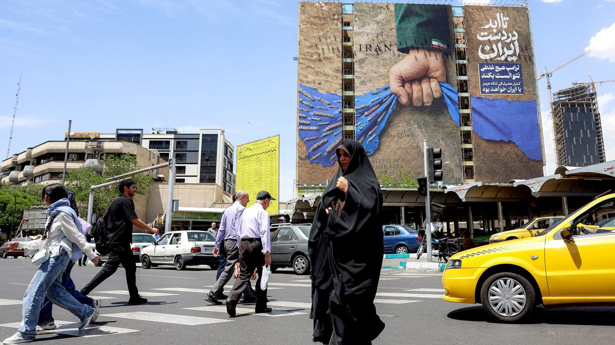 A woman crosses a street near a billboard on the facade of a building depicting the Strait of Hormuz with a caption in Persian reading "Forever in Iran's Hand", at Vanak Square in Tehran on May 6, 2026. The United States and Pakistan, a key mediator in the Middle East war, expressed new hope of talks leading to a peace deal with Iran on May 6, after President Donald Trump halted a plan to guide ships through the Strait of Hormuz. (AFP/Getty Images/TNS)