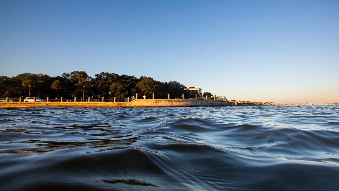 As high tide laps against the sea wall, tourists walk down the Battery in Charleston in 2020.