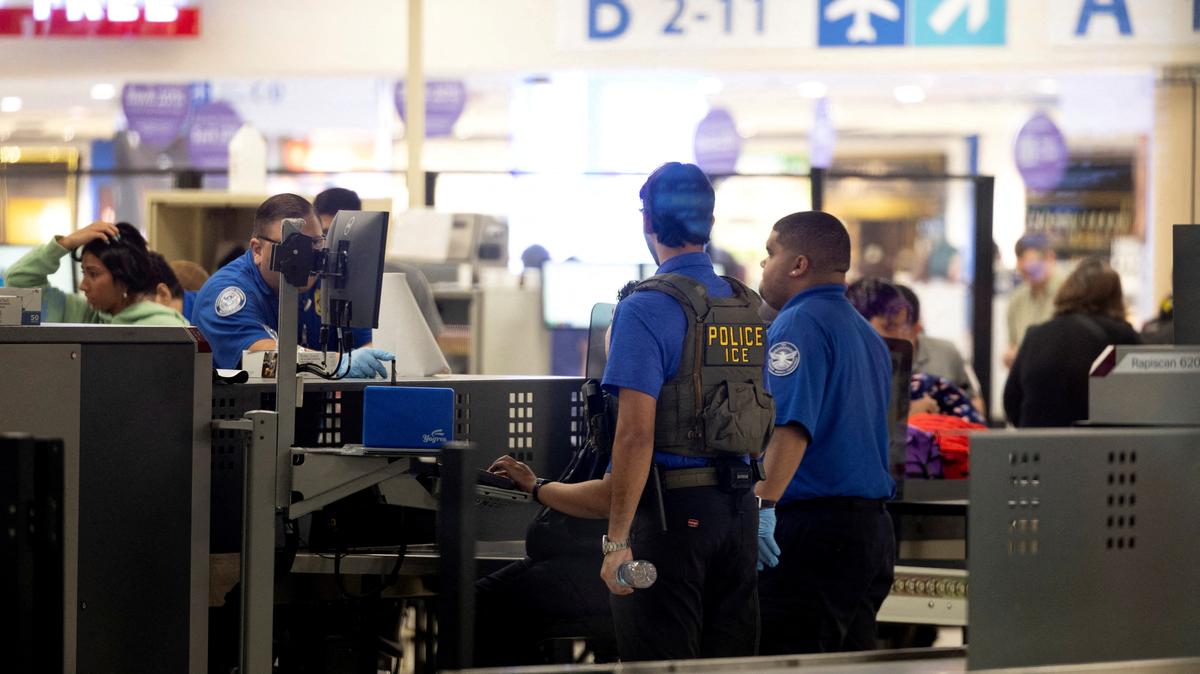 An Immigration and Customs Enforcement (ICE) agent assists Transportation Security Administration (TSA) officers as passengers are screened at a checkpoint at Luis Munoz Marin International Airport in Carolina, Puerto Rico, March 27, 2026. REUTERS/Ricardo Arduengo