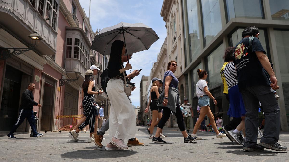 A woman walks through the streets of the downtown with an umbrella due to high temperatures, in Lima, Peru, February 25, 2024. REUTERS/Sebastian Castaneda