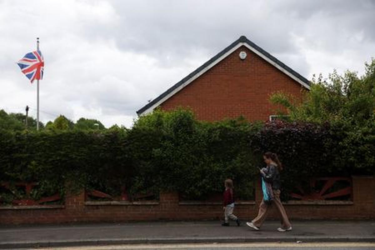 A woman walks with a child past a Union Jack flag ahead of the Makerfield by-election, triggered by Labour MP Josh Simons, who resigned as a minister in March, in Ashton-in-Makerfield, Britain, May 20, 2026. REUTERS/Temilade Adelaja