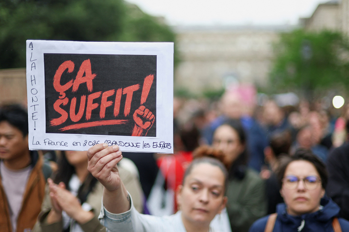 People attend a demonstration, amid nationwide calls to protest the handling by the criminal justice system of previous complaints involving child victims against the main suspect in the killing of 11-year-old Lyhanna, whose body was discovered near Fleurance after a days-long search, near the  Paris courthouse, France, June 8, 2026, in a protest supported by the #NousToutes movement. The sign reads: "That's enough". REUTERS/Gonzalo Fuentes