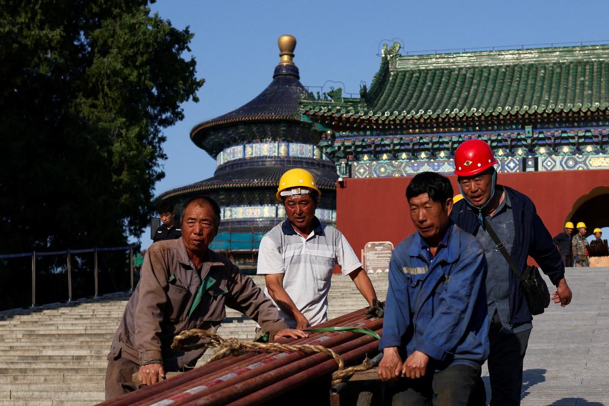 Construction workers pull a trolley with parts of scaffolding next to the Hall of Prayer for Good Harvests at the Temple of Heaven, or Tiantan Park, ahead of this week’s U.S. President Donald Trump's visit to China, in Beijing, China, May 11, 2026. REUTERS/Maxim Shemetov