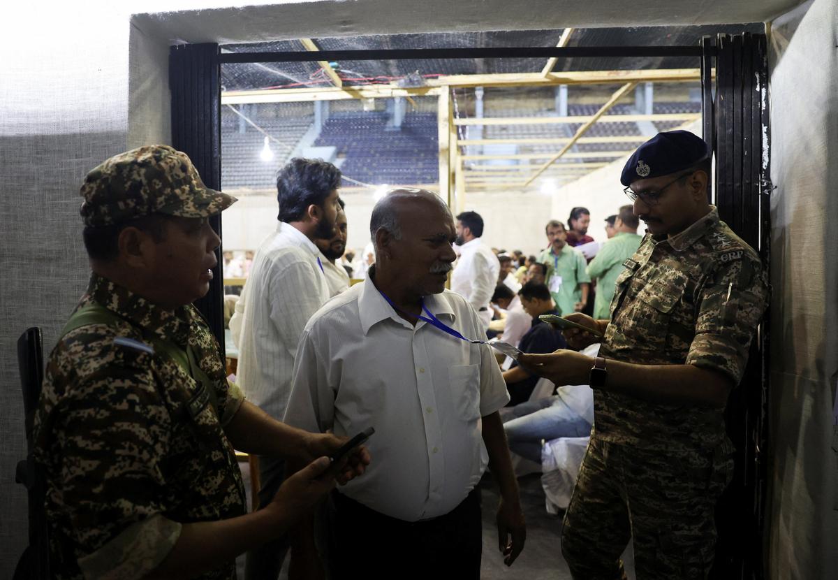 Security officials check the identification of an election official during vote counting of the West Bengal legislative assembly elections inside a counting centre in Kolkata, India, May 4, 2026. REUTERS/Sahiba Chawdhary