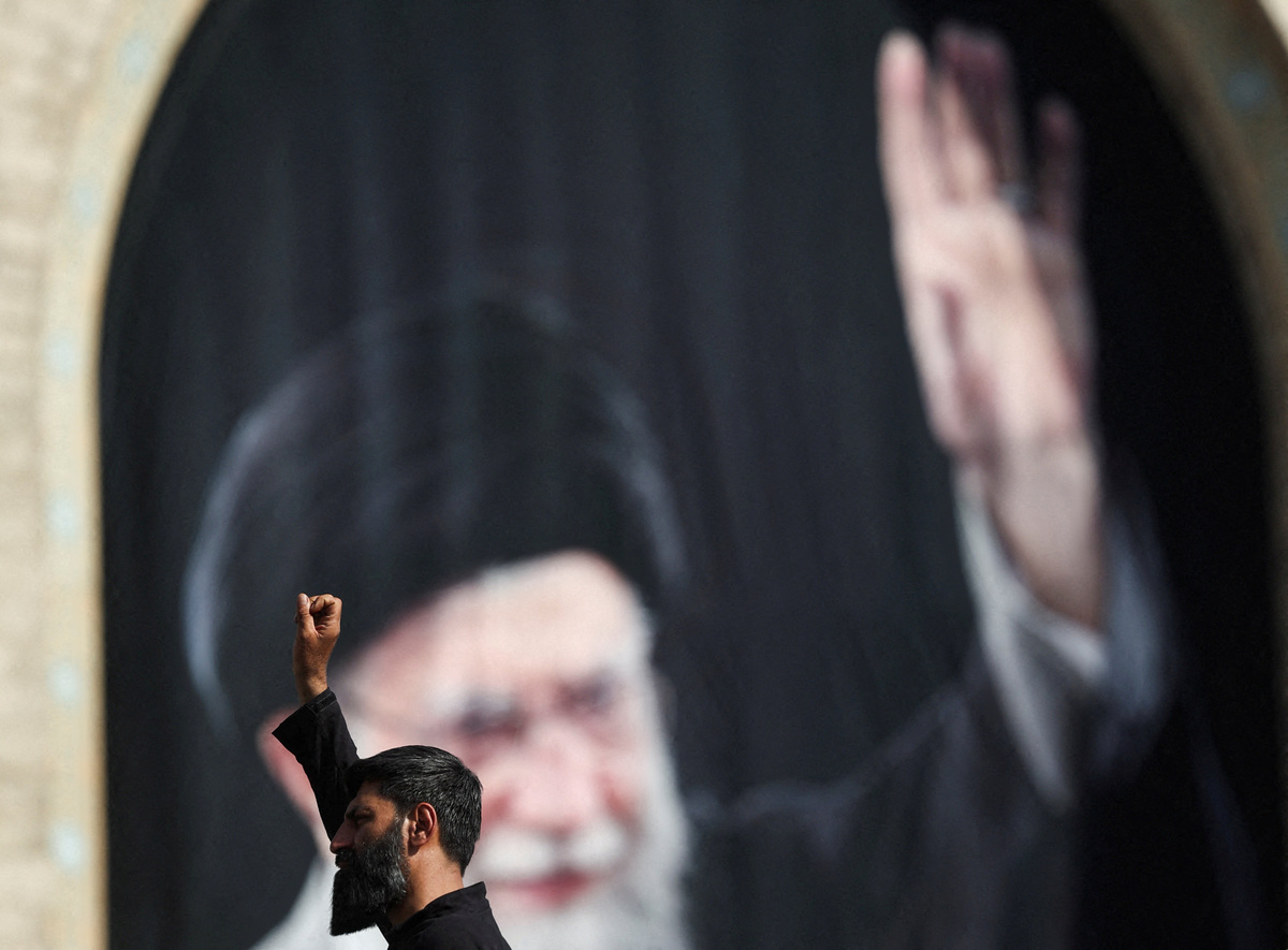 A man raises his hand with a banner of late Supreme Leader Ayatollah Ali Khamenei in the background on the day of a public farewell ceremony to pay their respects to Khamenei, who was killed on February 28 in Israeli and U.S. airstrikes, at the Imam Khomeini Grand Mosalla, in Tehran, Iran July 4, 2026.  Majid Asgaripour/WANA (West Asia News Agency) via REUTERS
