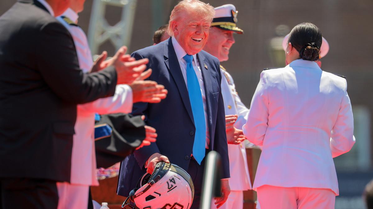 The 2026 U.S. Coast Guard Academy Class President Cadet Savannah Riera, right, gifts U.S. President Donald Trump a football helmet during the commencement ceremony on Cadet Memorial Field at the United States Coast Guard Academy on Wednesday, May 20, 2026, in New London, Connecticut. This is the 145th U.S. Coast Guard commencement. (Chip Somodevilla/Getty Images/TNS)
