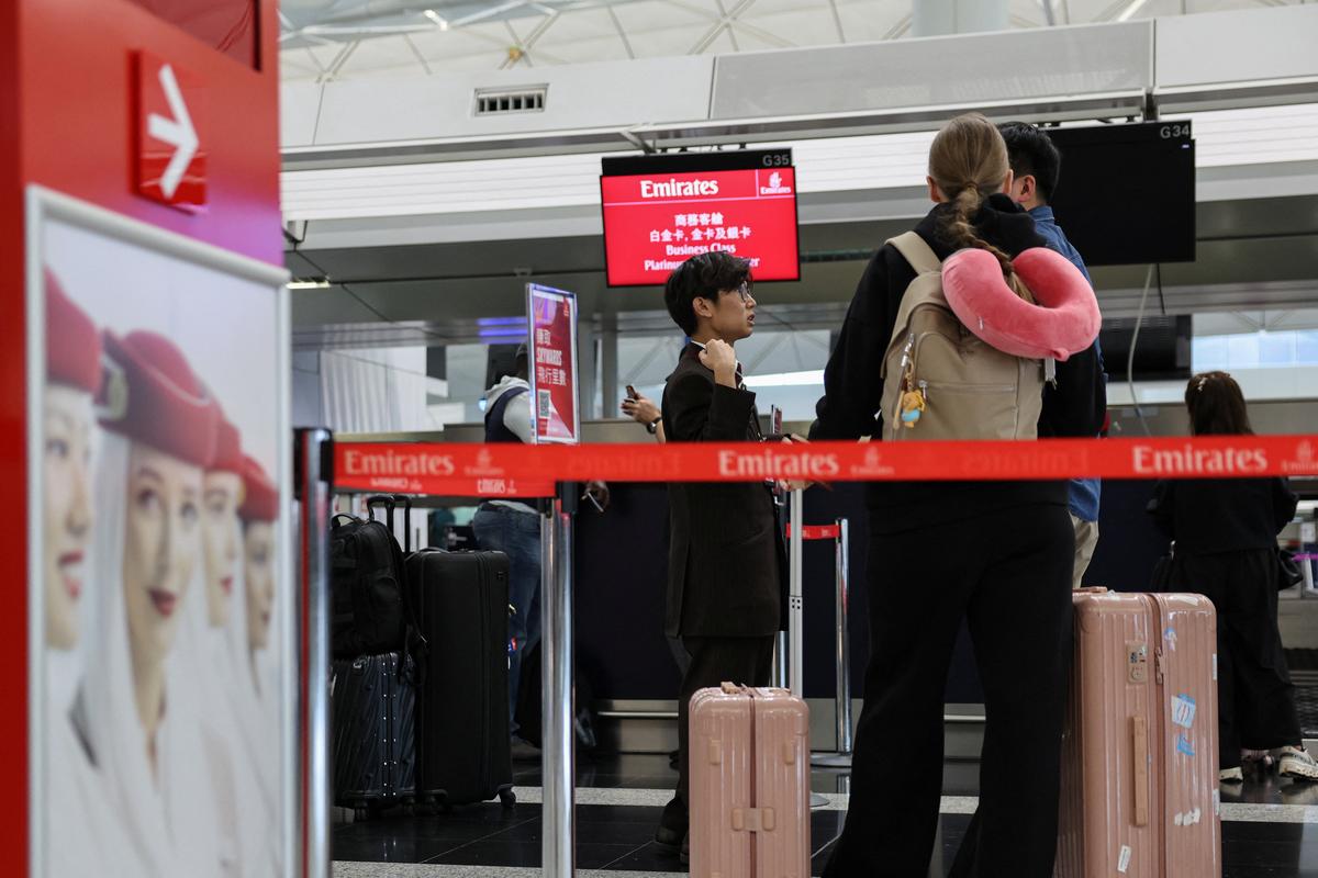 FILE PHOTO: Emirates Airlines passengers inquire about cancelled flight to Dubai at the check-in counter at Hong Kong International Airport, in Hong Kong, China, March 2, 2026. REUTERS/Tyrone Siu/File Photo