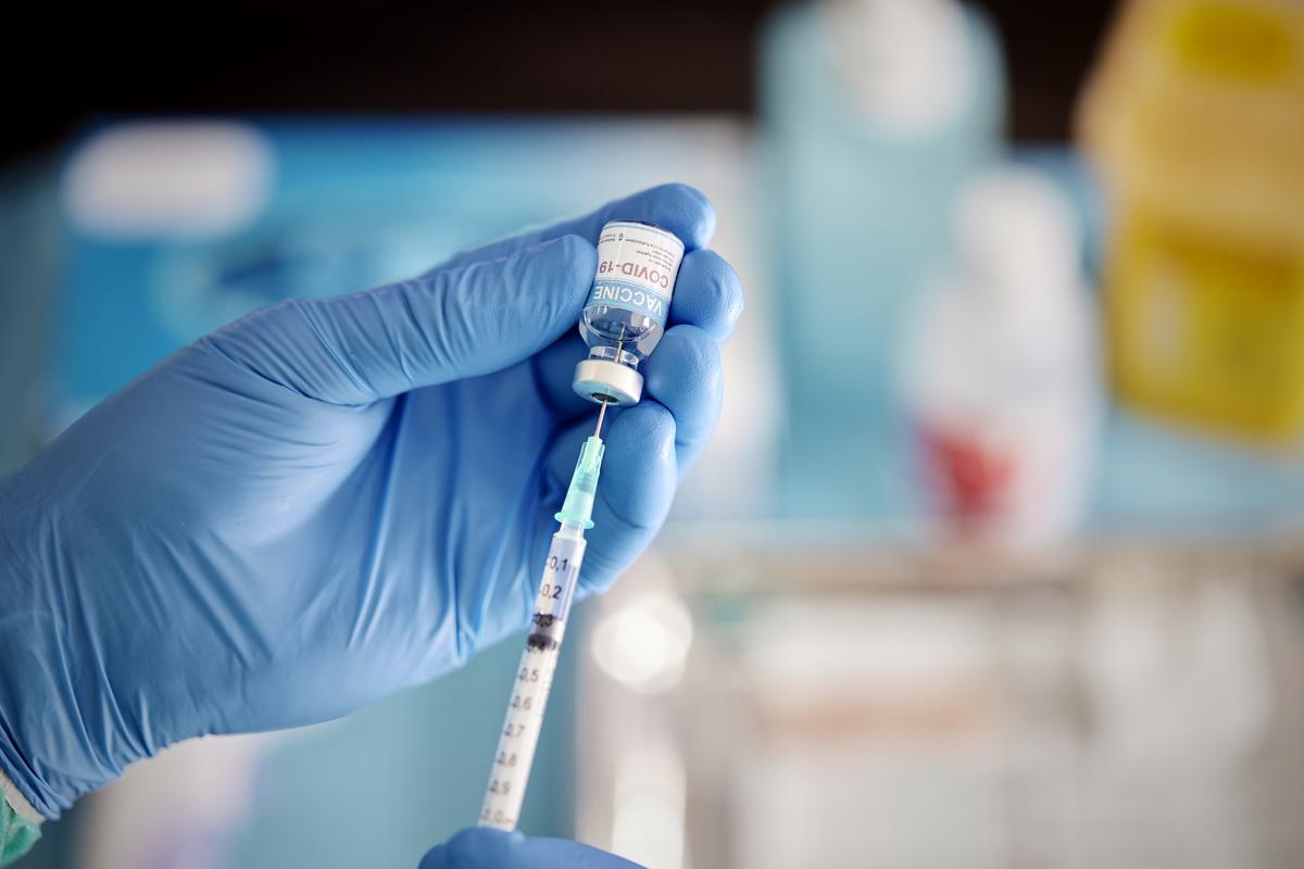 A health care worker pulling COVID-19 vaccine liquid from vial to vaccinate a patient.