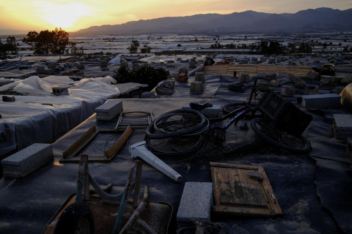 Roofs of shanties are weighed down with stones, bicycles and hand carts to keep plastic sheeting from blowing away in the wind at a shanty town where documented and undocumented migrants from Morocco and sub-Saharan Africa live next to plastic-covered greenhouses in Almeria province, home to Europe’s largest concentration of agricultural greenhouses, in Nijar, Spain, April 23, 2026. Charities have long criticised living conditions around the Almería greenhouses, estimating around 10,000 people live in substandard housing, with at least 70% undocumented. REUTERS/Nacho Doce