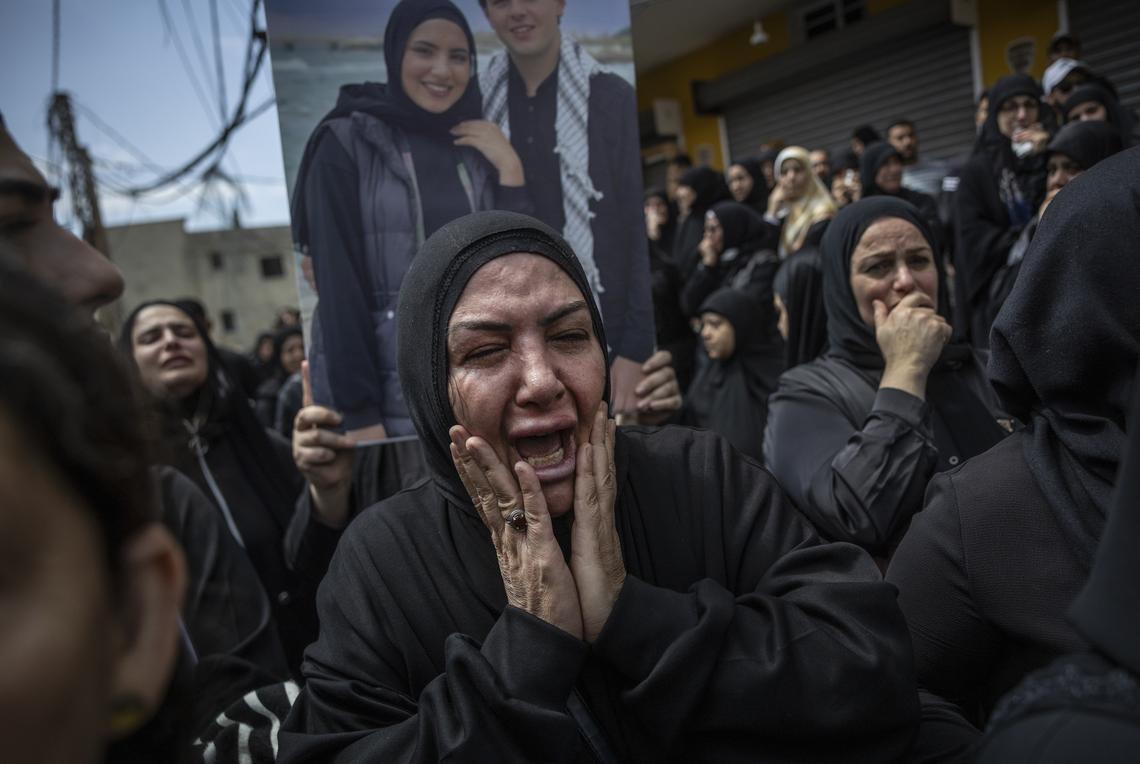 Family members grieve as the coffins of their loved ones arrive in a convoy of ambulances in the southern Lebanese village of Bazourieh for a mass funeral, on Monday, April 20, 2026. Families gathered for the funeral of nine people -- both Hezbollah fighters and civilians -- who were killed in recent weeks (David Guttenfelder/The New York Times)