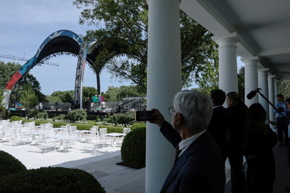 Reporters leaving the Oval Office take pictures as workers continue preparations on a temporary arena that will host the UFC Freedom 250 fight event in June on the South Lawn of the White House in Washington, D.C., U.S., June 4, 2026. REUTERS/Jonathan Ernst