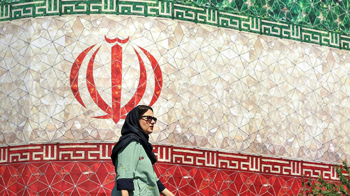 A woman walks past a billboard displaying Iran's national flag at Enghelab Square in Tehran on Sunday. U.S. and Iranian officials said they had agreed on a framework to end their war, halt the U.S. blockade of Iran and reopen the Strait of Hormuz.