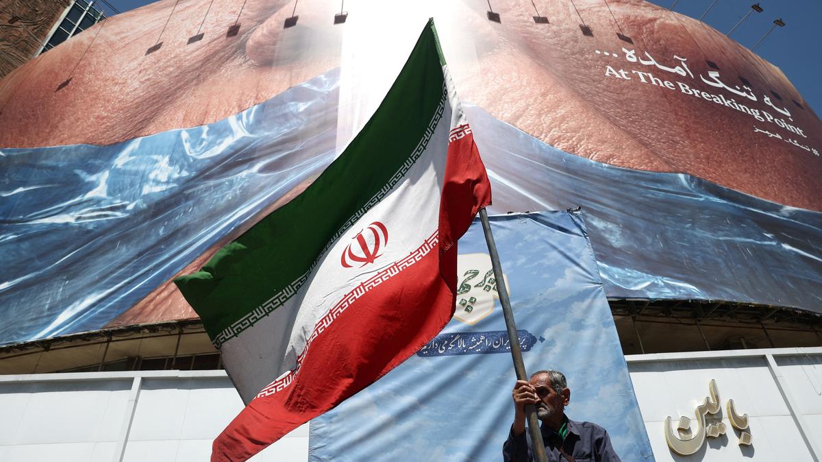 A man holds an Iranian flag near an anti-U.S. billboard depicting U.S. President Donald Trump and the Strait of Hormuz, in Tehran, Iran, May 30, 2026. Majid Asgaripour/WANA (West Asia News Agency) via REUTERS