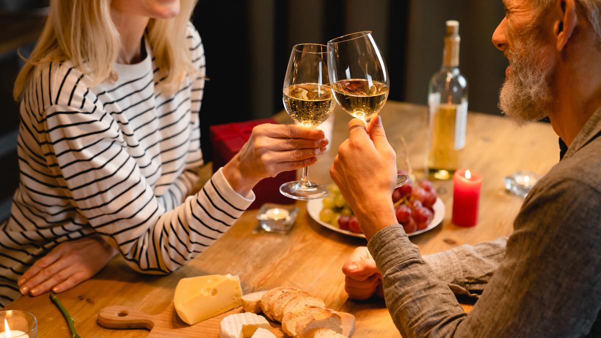 Cropped shot of cheerful senior couple clinking glasses of wine on a romantic date