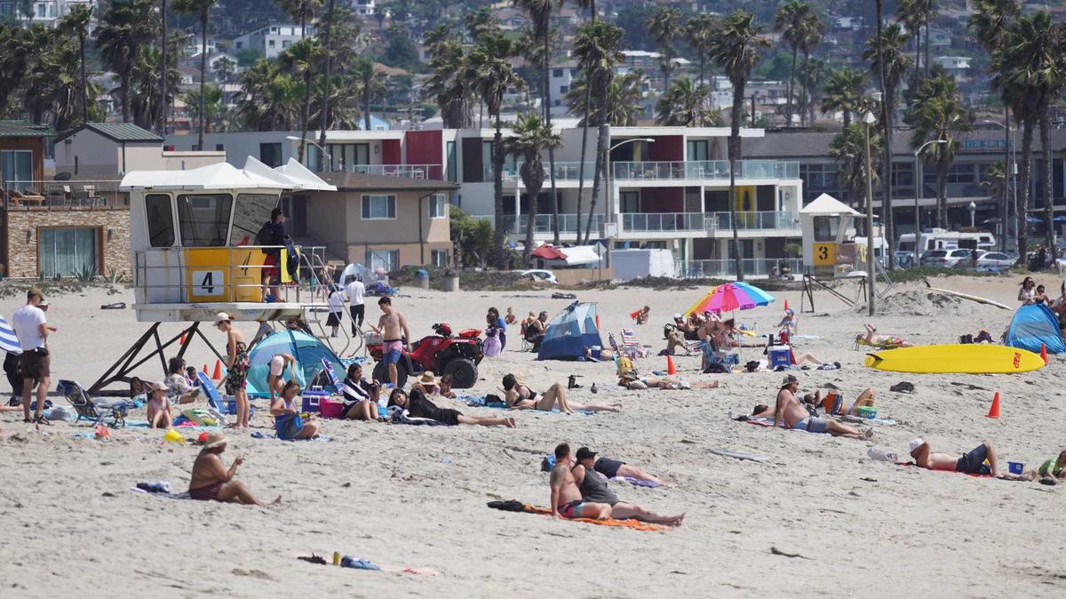 Over the last 16 months, San Diego County home price gains have not kept up with inflation. Pictured:  Beachgoers near homes in Ocean Beach in late June. (Michael Ho / The San Diego Union-Tribune)