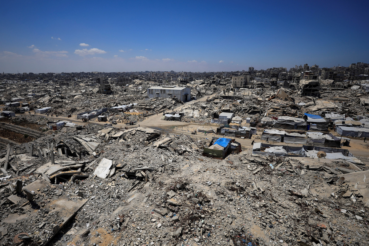 Palestinians make their way past the rubble of residential buildings destroyed during the Israeli offensive as displaced people shelter in tents, in Gaza City, June 15, 2026. REUTERS/Dawoud Abu Alkas