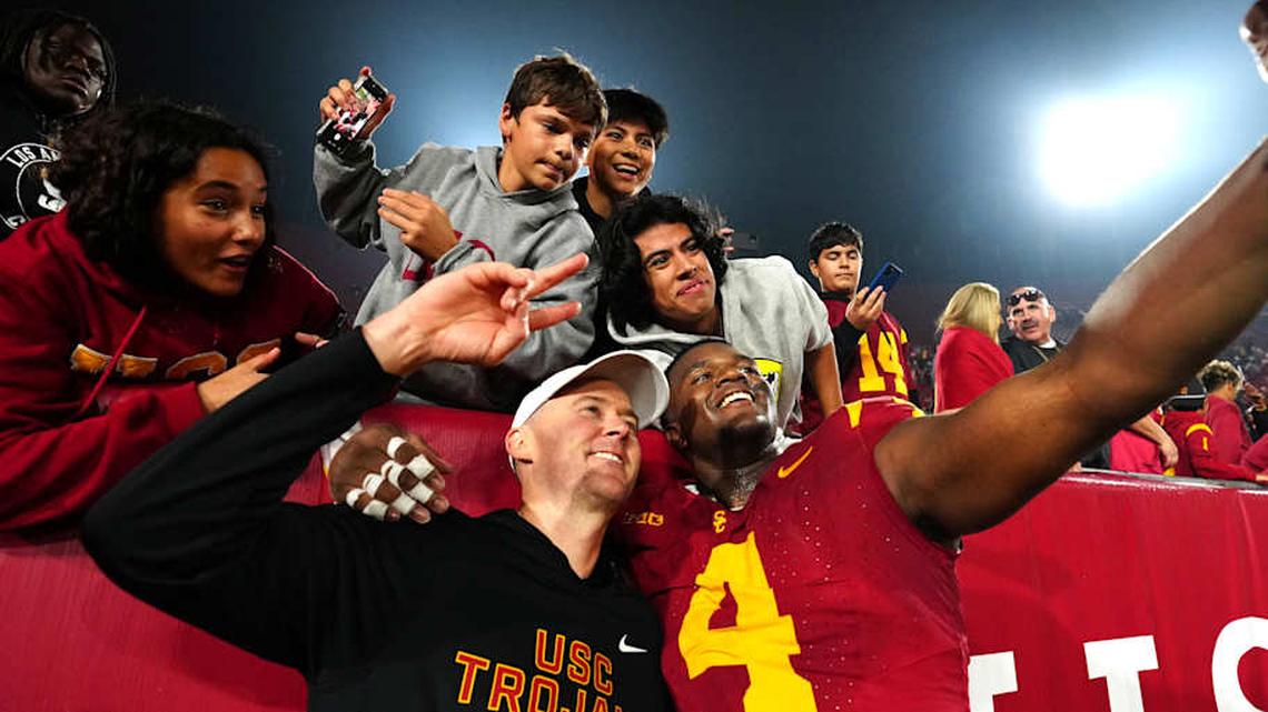  Nov 29, 2025; Los Angeles, California, USA; Southern California Trojans head coach Lincoln Riley (right) and defensive tackle Jahkeem Stewart (4) pose with fans after the game against the UCLA Bruins at United Airlines Field at Los Angeles Memorial Coliseum. Mandatory Credit: Kirby Lee-Imagn Images | Kirby Lee-Imagn Images 