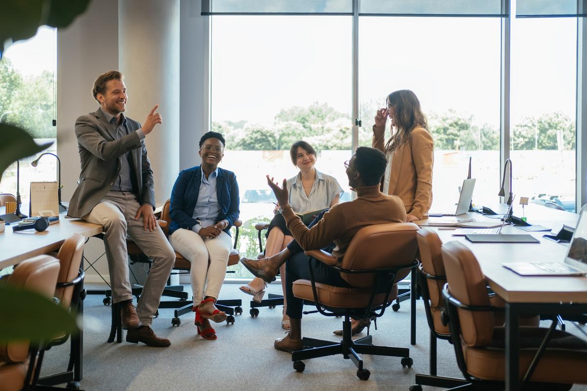  Five employees sit together in an office. 