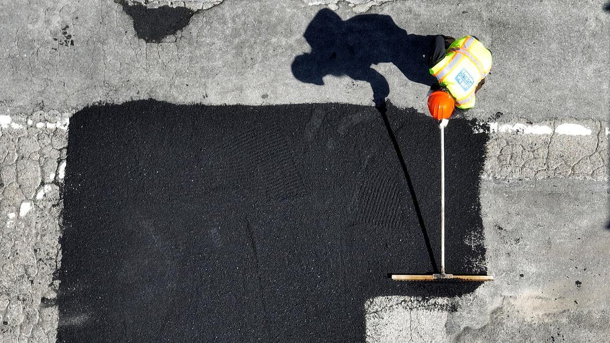 In an aerial view, San Francisco Department of Public Works (SFDPW) worker Chris Solorzano uses a grading rake to smooth over asphalt as he repairs a pot hole on March 24, 2023, in San Francisco, California. (Justin Sullivan/Getty Images/TNS)