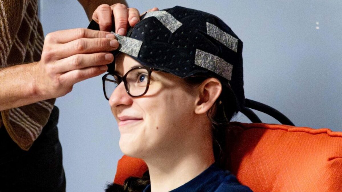 Co-authors Owen Griffith, standing, and Maddie McLaughlin demonstrate the head cooling cap used in the study. (Jaydyn Isiminger / Penn State via SWNS). 