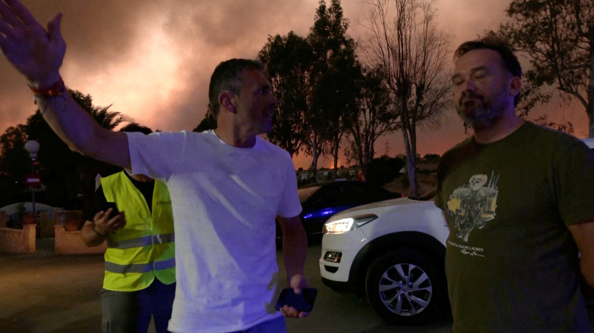 Francisco Reyes, mayor of Los Gallardos, gestures while speaking to a man next to him, as smoke rises in the background during a wildfire in Los Gallardos, Spain, July 9, 2026, in this screengrab taken from a handout video. Forta/Handout via REUTERS