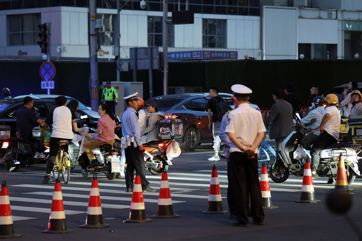 Police officers keep watch at a junction near CITIC Tower, also known as China Zun, where damage is visible on a high floor of the exterior, in Beijing, China June 26, 2026. REUTERS/Maxim Shemetov