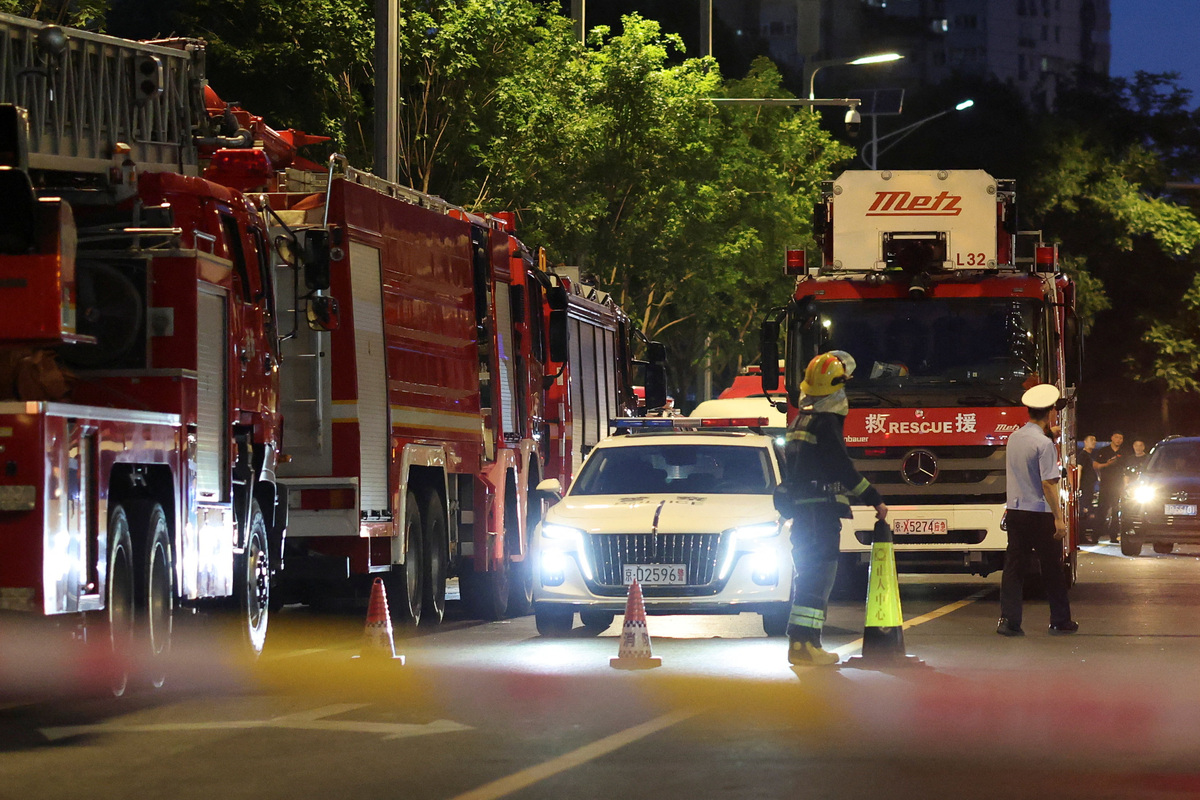 Rescue workers stand near firetrucks behind a cordon line on a road next to CITIC Tower, also known as China Zun, in Beijing, China June 26, 2026. REUTERS/Maxim Shemetov