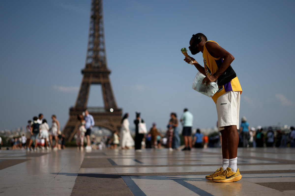 A person eats ice cream in front of the Eiffel Tower during a heatwave in Paris, France, June 27, 2026. REUTERS/Tom Nicholson