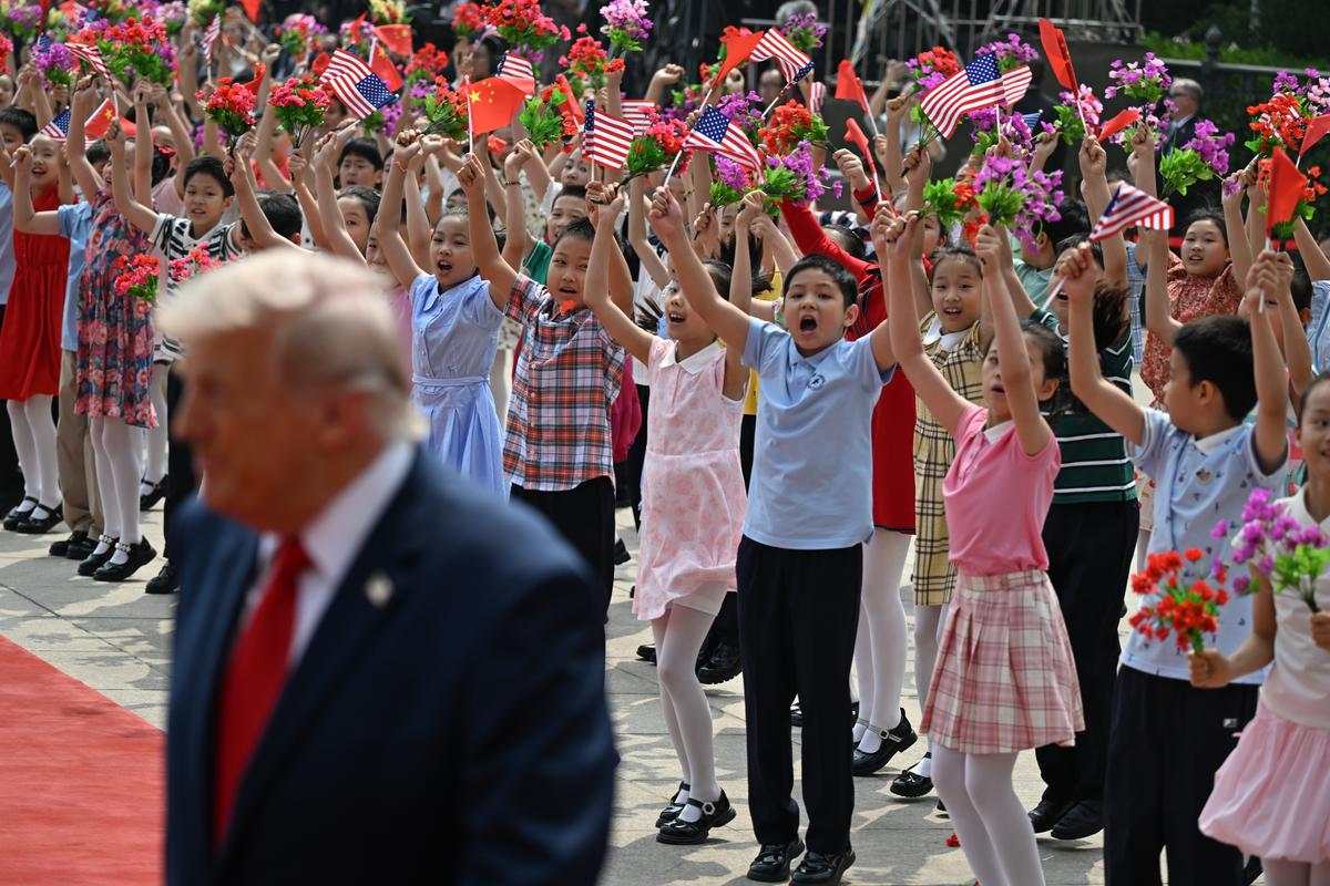 Children waving American flags welcome President Donald Trump, foreground, to the Great Hall of the People in Beijing during his two-day summit with President Xi Jinping of China, on Thursday, May 14, 2026. During the first U.S. presidential visit to China in nearly a decade, Xi delivered a warning on Taiwan, saying that the issue, if handled poorly, could lead to conflict and "an extremely dangerous situation." (Kenny Holston/The New York Times)..