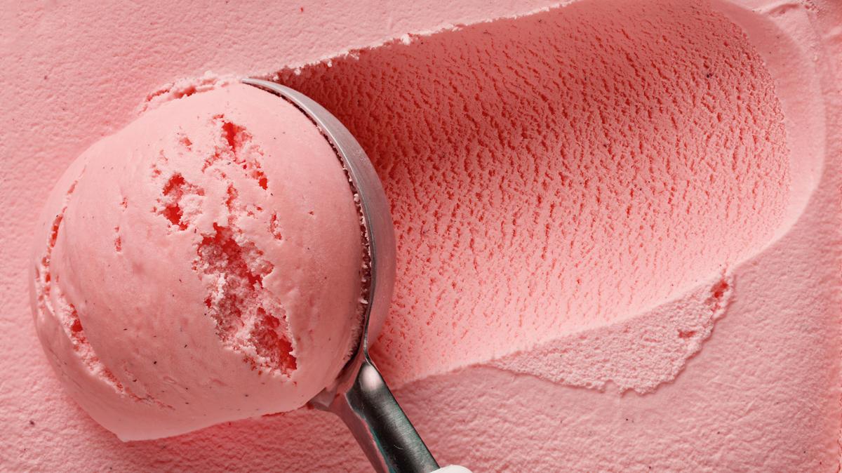 pink strawberry ice cream ball in a spoon, top view