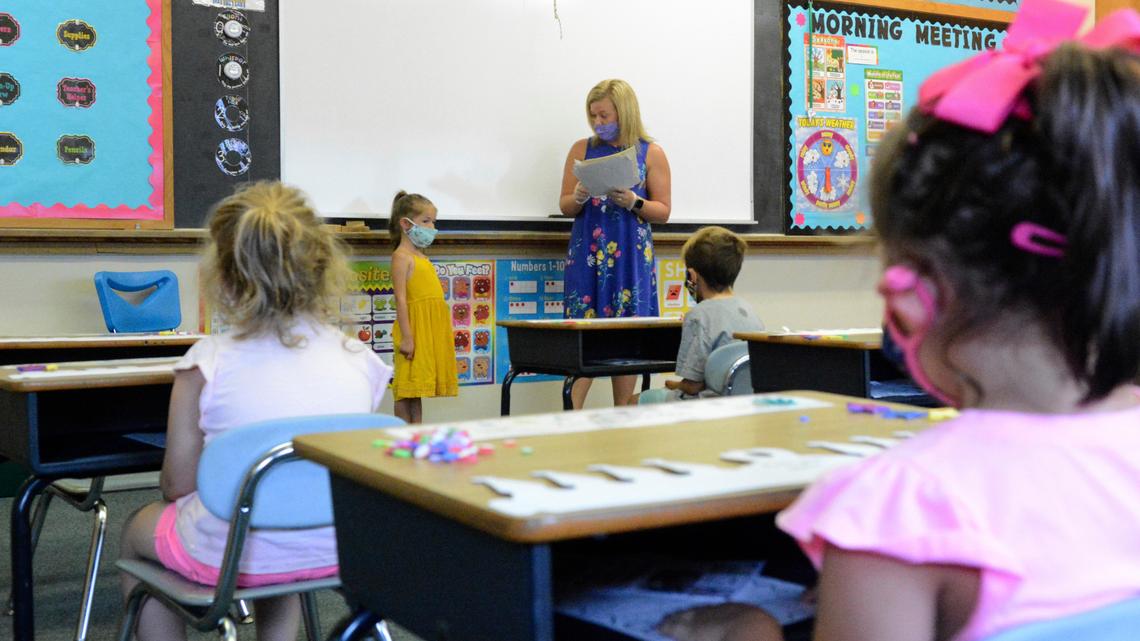 FILE - In this Aug. 27, 2020, file photo, Hadlee Yohn, back left, of Minersville, stands in front of the class as teacher Ashley Thompson, of Tremont, back right, reads information about Yohn during kindergarten orientation at St. Nicholas Ukrainian Catholic School in Minersville, Pa. Moves reflecting takeaways from pandemic experiences are being incorporated into many teacher preparation programs. Digital tools, online instruction, mental and emotional wellness are happening not just in what aspiring educators are learning, but how. More programs are using tools such as computer simulation training and virtual field supervision of student-teaching. (Lindsey Shuey/Republican-Herald via AP, File)