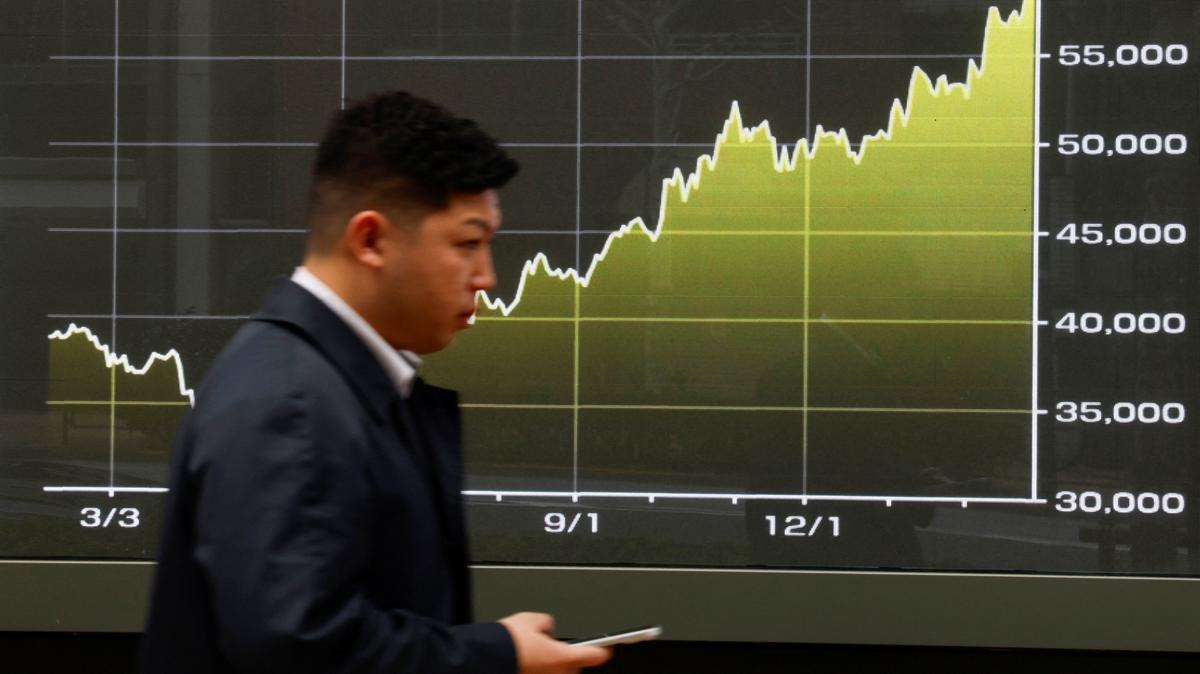 A man walks past a screen displaying a graph showing Japan's Nikkei share average within this year outside a brokerage in Tokyo, March 2, 2026. REUTERS/Manami Yamada