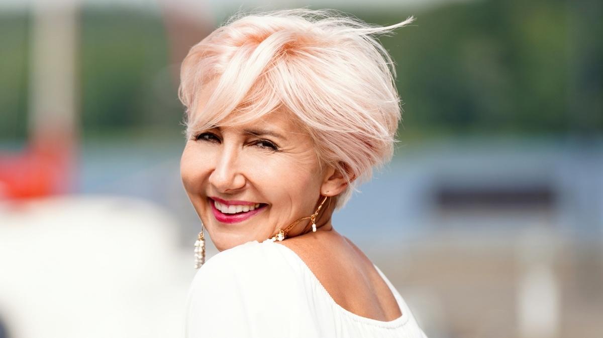 Beautiful adult blonde woman with short hair posing outdoor, smiling and looking at the camera. Sunny, summer day.