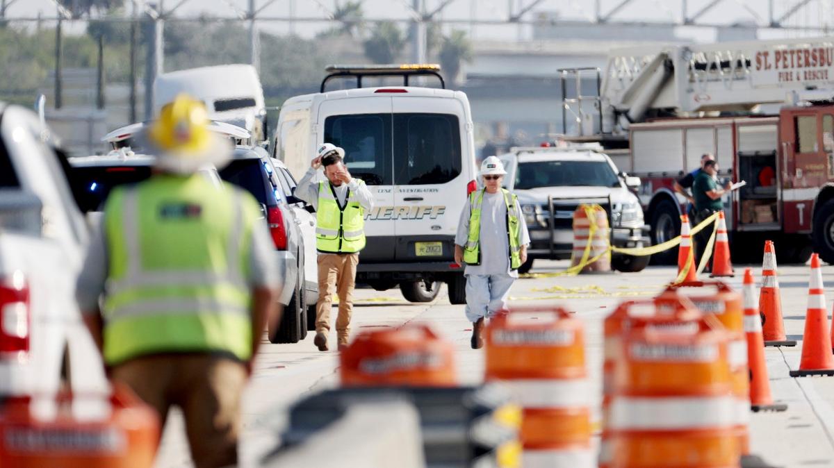 Trabajadores de la construcción caminan desde la escena en los carriles hacia el oeste de la I-275 cerca de Gandy Boulevard el viernes 23 de septiembre de 2022, en St. Petersburg, Florida, donde el agente Michael Hartwick, de 51 años, murió tras ser golpeado por una cargadora frontal durante la noche. El agente Michael Hartwick, quien trabajaba en un turno nocturno para proporcionar seguridad en una zona de construcción murió tras ser golpeado por un trabajador que operaba una cargadora frontal, dijeron las autoridades.