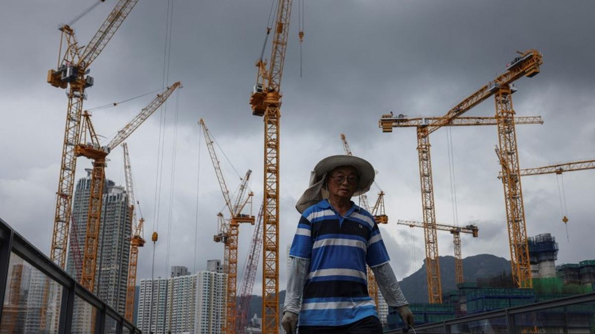 A man walks near a construction site for a residential development in Kai Tak, Hong Kong, China, May 6, 2025. REUTERS/Tyrone Siu