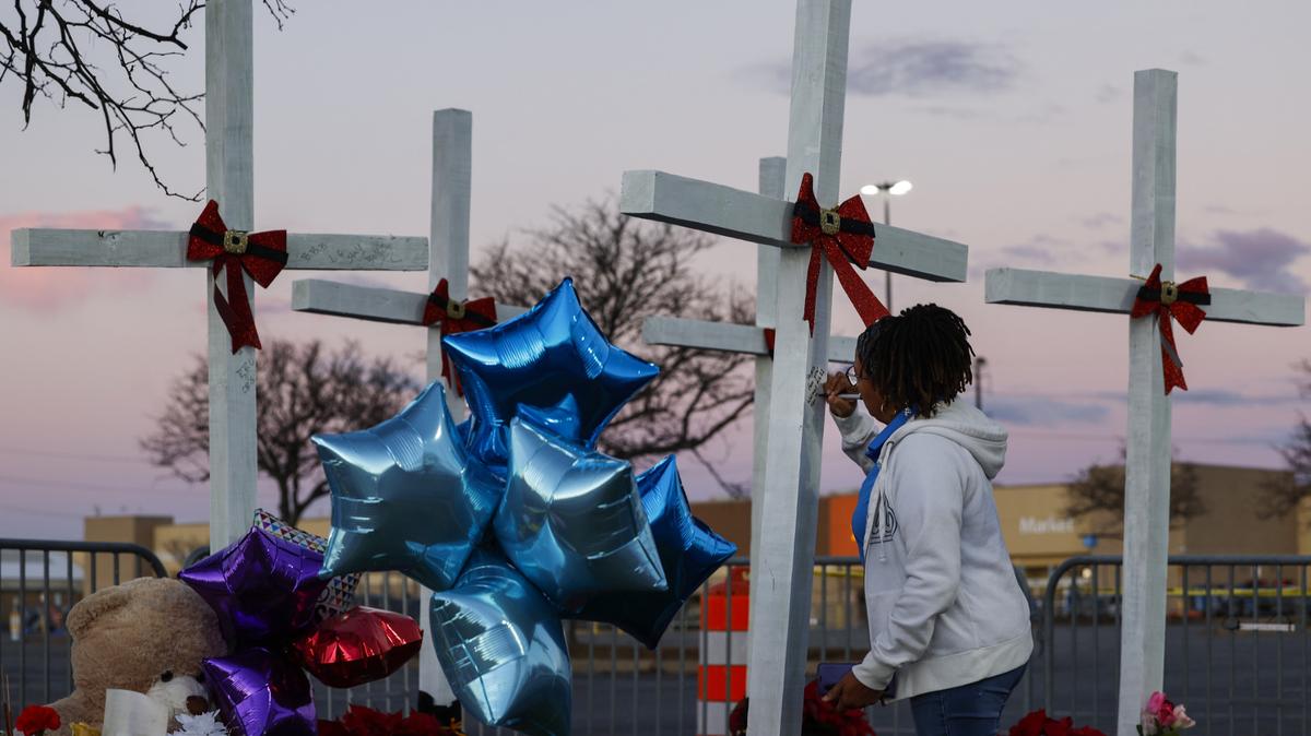 Frances Shelton, una empleada de Walmart #1682 Chesapeake Square Ring Road, firma una nota en una cruz de madera cerca del lugar de un tiroteo en el Chesapeake Walmart Supercenter, el 28 de noviembre de 2022 en Chesapeake, Virginia. Una empleada de la tienda, Donya Prioleau, demandó a Walmart por $50 millones debido a supuesta negligencia en la retención continua del atacante armado Andre Bing.