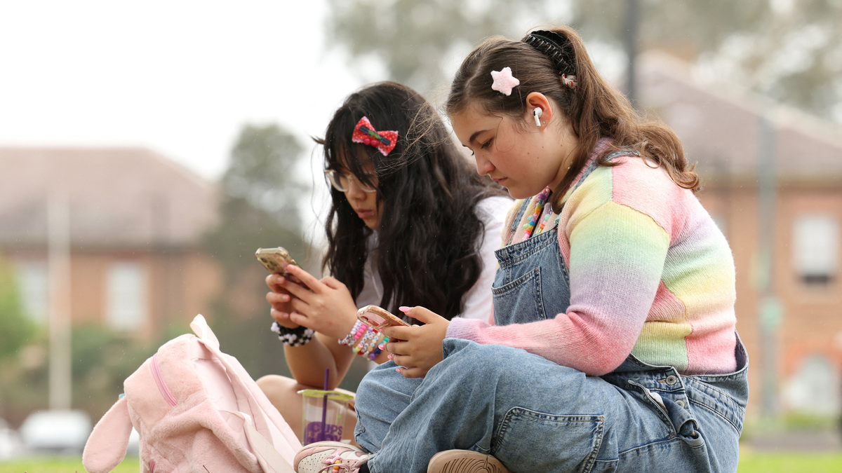 Annie Wang, 14, and Ayris Tolson, 15, use their mobile phones, ahead of Australia’s social media ban for users under 16, in Sydney, Australia, November 22, 2025. REUTERS/Hollie Adams