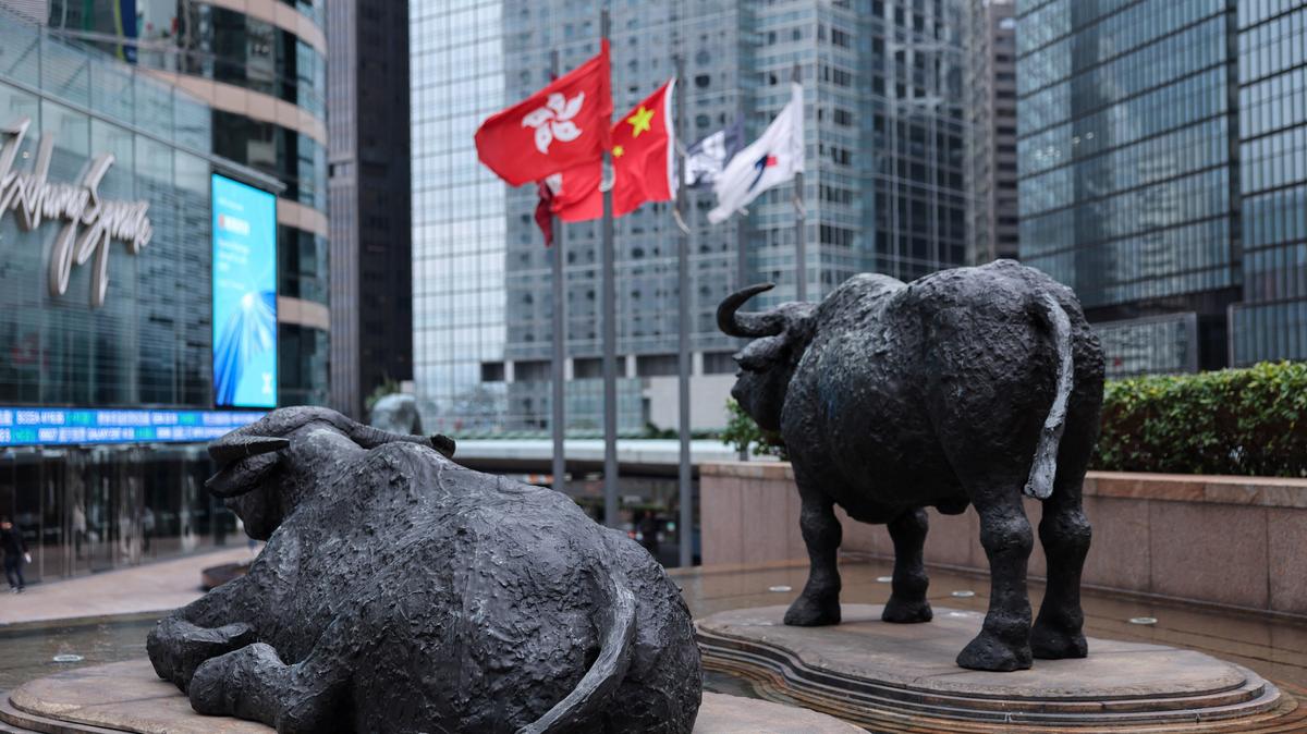 Bull statues near screens showing the Hang Seng stock index and stock prices outside Exchange Square, in Hong Kong, China, February 3, 2026. REUTERS/Tyrone Siu